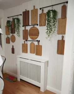 wooden cutting boards and breadboards layered against a white tiled kitchen wall