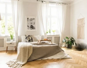 bedroom with two windows, one dressed with curtains and one left bare